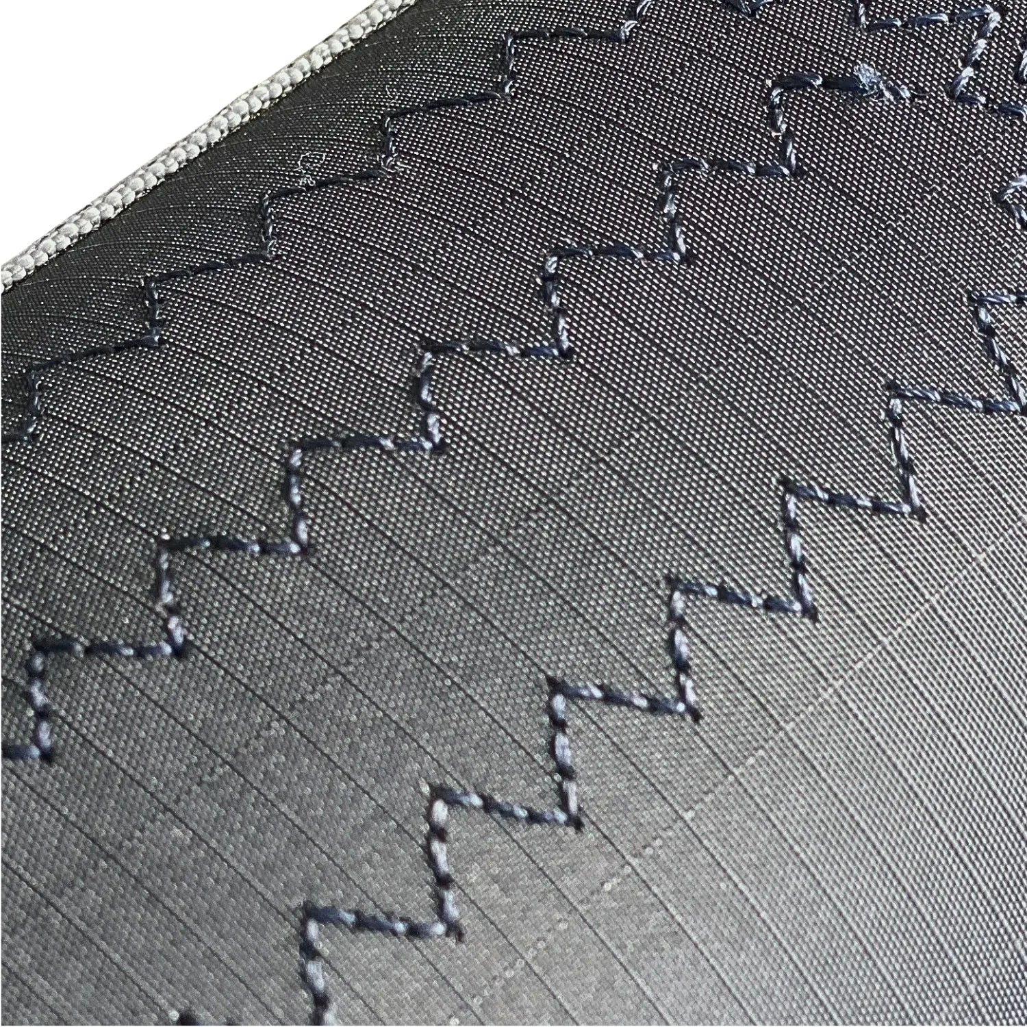 Macro photography of the UV-stabilized ripstop AeroCasing™ fabric, highlighting the high-tenacity weave and load-bearing stitch patterns.
