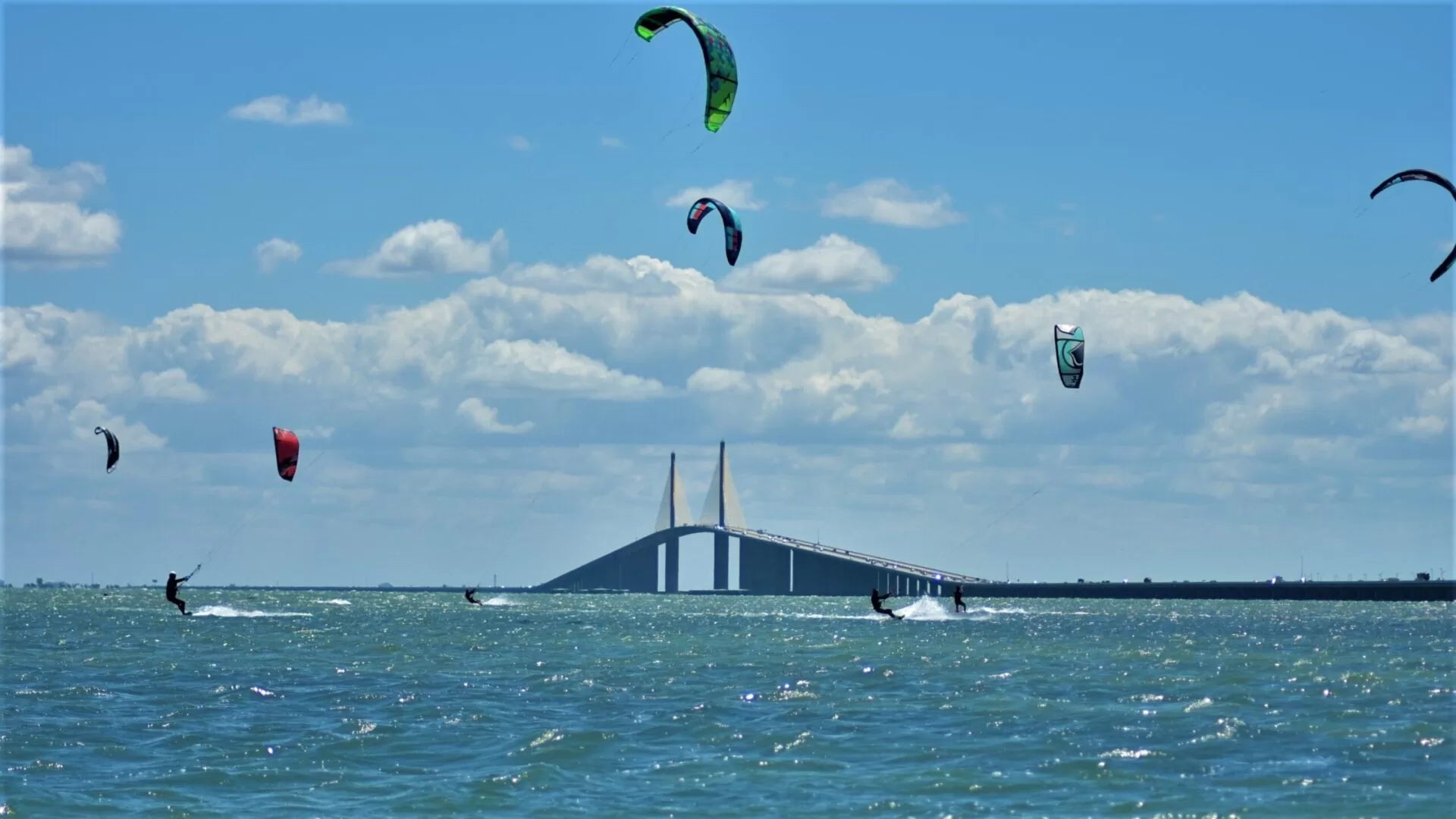 Professional kiteboarders navigating extreme wind conditions at the Sunshine Skyway Bridge in St. Petersburg, Florida. This high-intensity coastal environment represents the genesis of Sebba Shade, where our founders first utilized high-pressure inflatable airframes to withstand violent wind shears and offshore gales.
